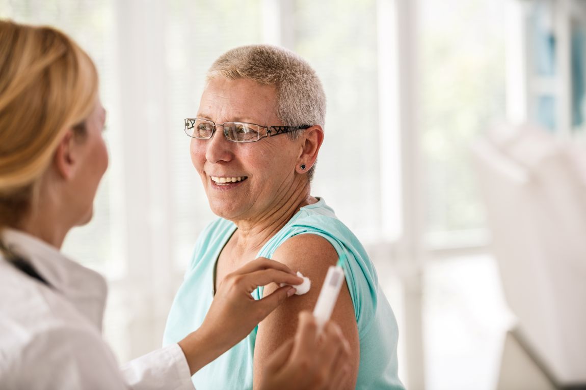 doctor puts cotton ball on woman's shoulder after allergy shot